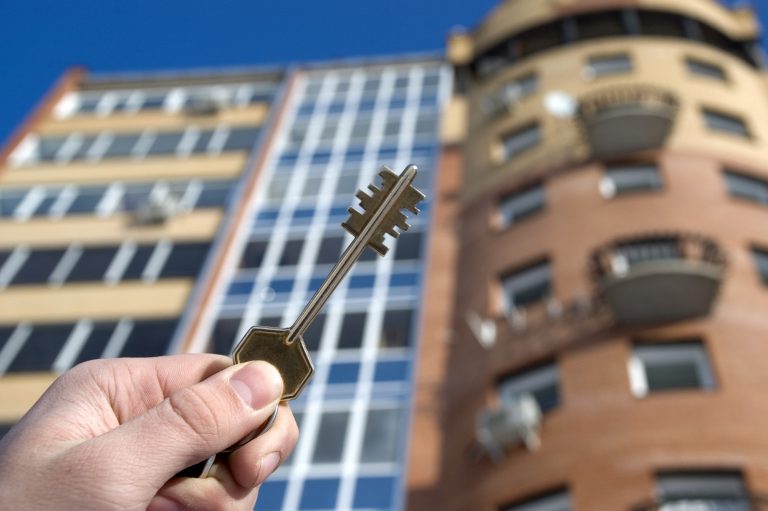 Bradford Condo owner with key in and in front of building.